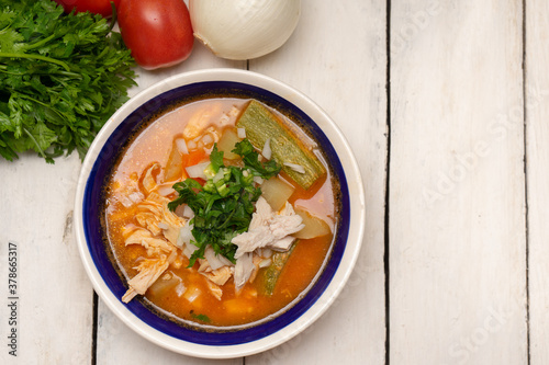 Mexican chicken soup with vegetables and rice on white background