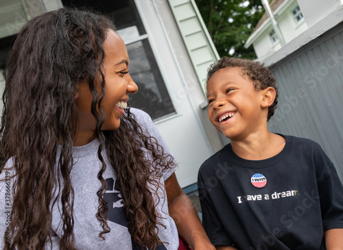 Young African AMerican boy wearing an Ivoted sticker laughing with his multi-racial mother