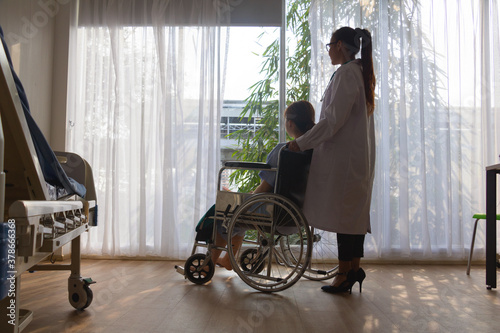 Doctor carrying woman patient on  Wheelchair. They are in hospital. disabled person,help. Photo concept depression and Patient. photo