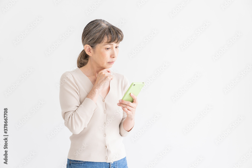 スマートフォンを見るシニア女性 考える スマートフォンを見るシニア女性 考える