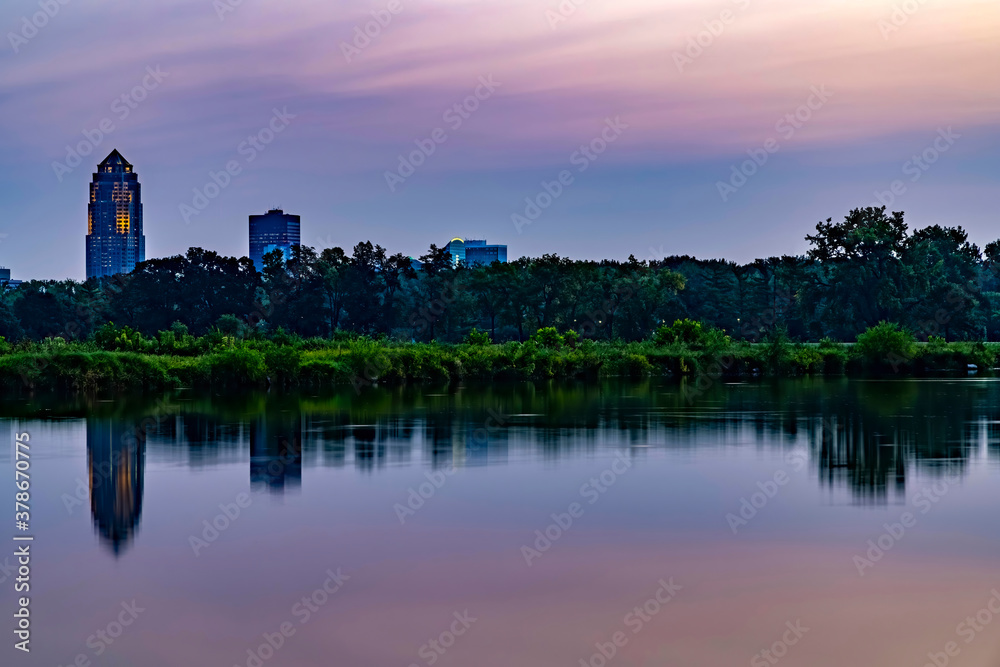 Des Moines skyline reflecting in a lake at sunrise.
