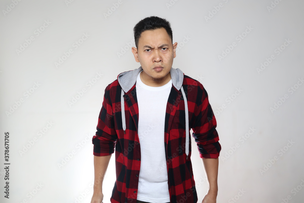 Fototapeta premium Portrait of funny Asian man showing cynical unhappy angry facial expression, looking at camera over white