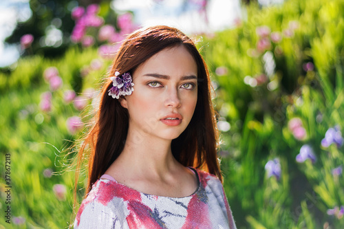 rostro de joven hermosa de cabello castaño y ojos claros con un fondo natural. hermosa modelo natural con fondo de flores