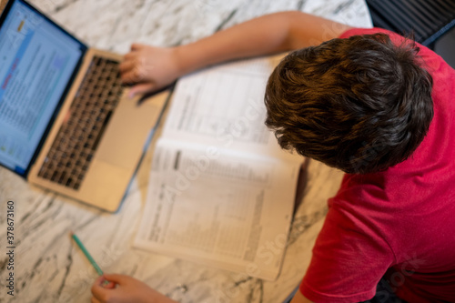 A young kid is doing homework at home during the pandemic quarantine 