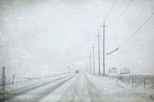 Original textured winter photograph of a lonely country road in the snow with black birds sitting a a telephone wire photo