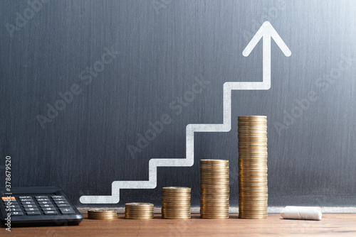 Financial growth and investment progress. Stack of coins and calculator. Steps and arrow drawn on blackboard. photo