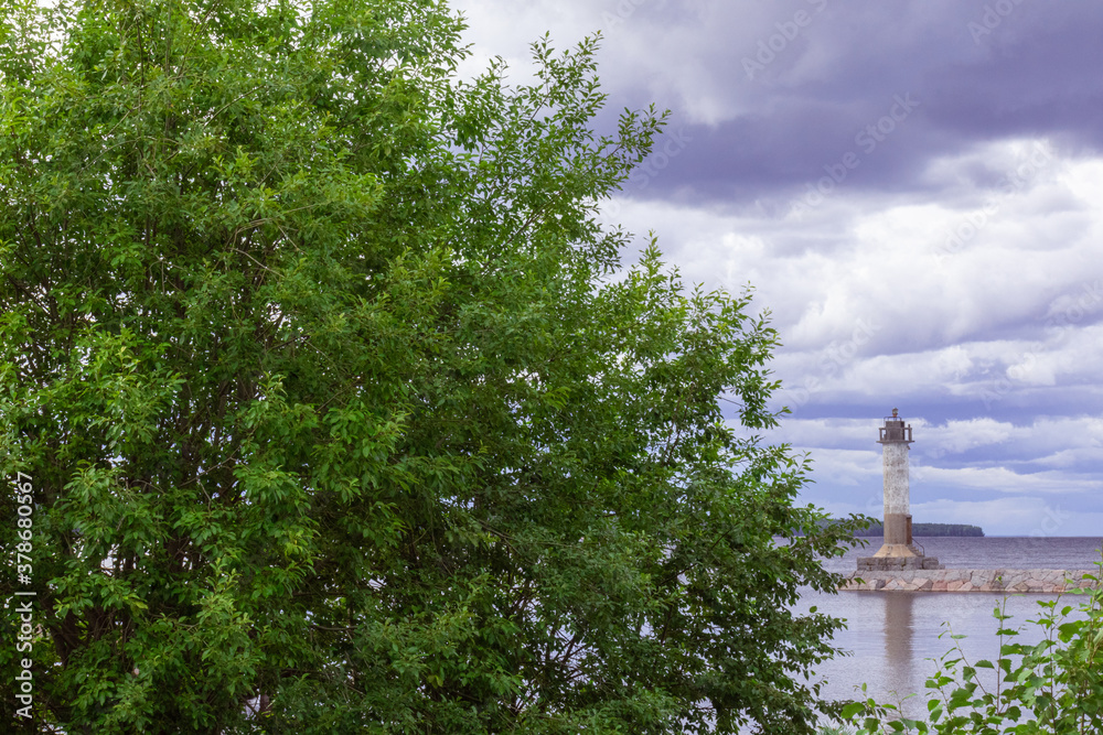 Old lighthouse on the island with a beautiful sky and a Park with green trees