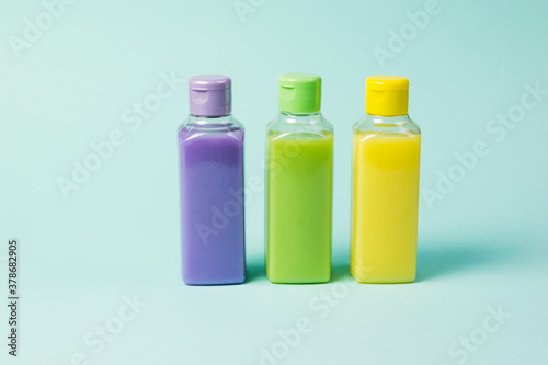 Three colored plastic bottles on a light blue background.
