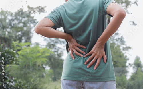 Closeup hands of woman touching her back pain in healthy concept on nature background.