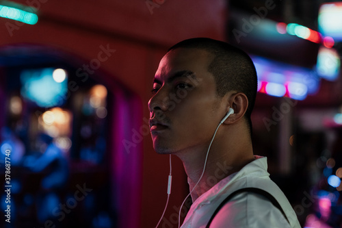 Slika na platnu Business man listen to music with earphones at night street market