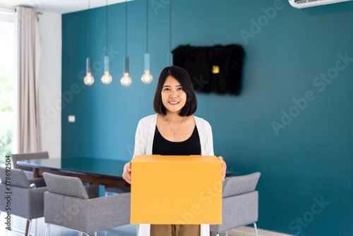 Happy asian woman carrying big cardboard box at new home,Moving day