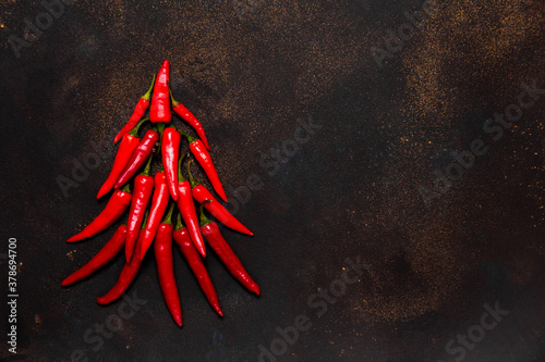 New year symbol: xmas tree made from red hot chilli peppers on dark background. Culinary christmas card with space for text top view