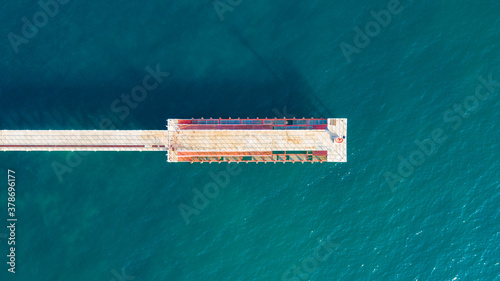 Aerial top view of old pier. View from the flight to a pier with a lighthouse on a sunny day. wooden pier with ocean water, marina. Screensaver on your desktop.