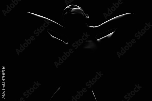 Nude Woman silhouette under light in the dark studio