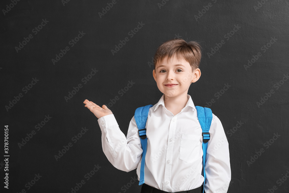 Little schoolboy showing something on dark background Little schoolboy showing something on dark background