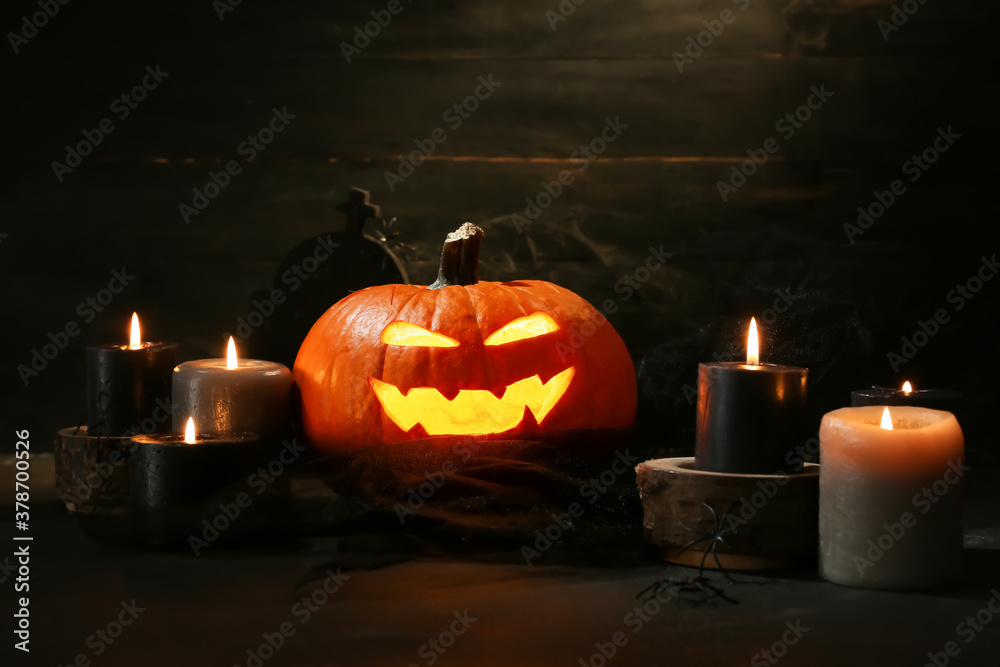 Obraz premium Carved Halloween pumpkin and candles on dark background