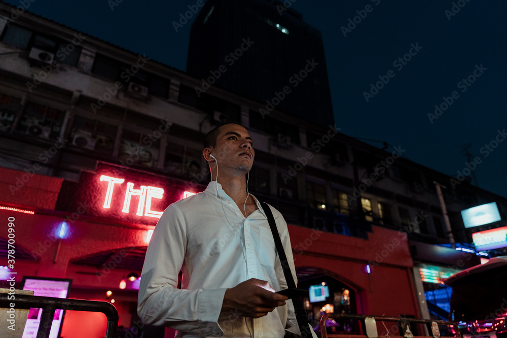 Obraz premium Business man listen to music with earphone at night.