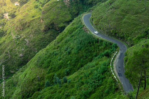 A road in the green mountains with a car.