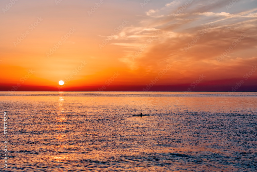 Sunrise over Mediterranean Sea with swimming woman