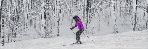 Alpine skiing skier going dowhill against snowstorm snow covered trees banner panoramic.