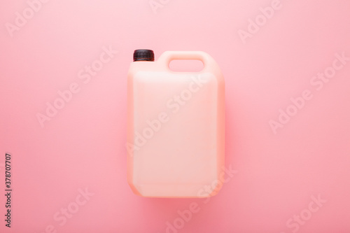 5L plastic container on light pink table background. Pastel color. Cleaning detergent, washing liquid or body care product. Closeup. Empty place for text or logo. Top down view.  photo