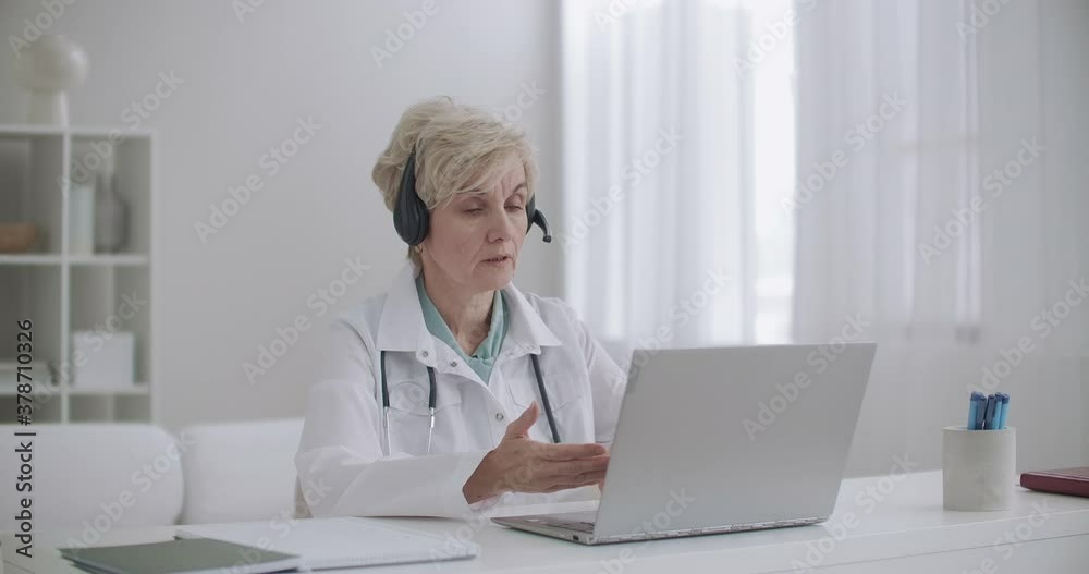 online appointment with therapist, aged woman is sitting at office in clinic and consulting people remotely by internet online appointment with therapist, aged woman is sitting at office in clinic and consulting people remotely by internet