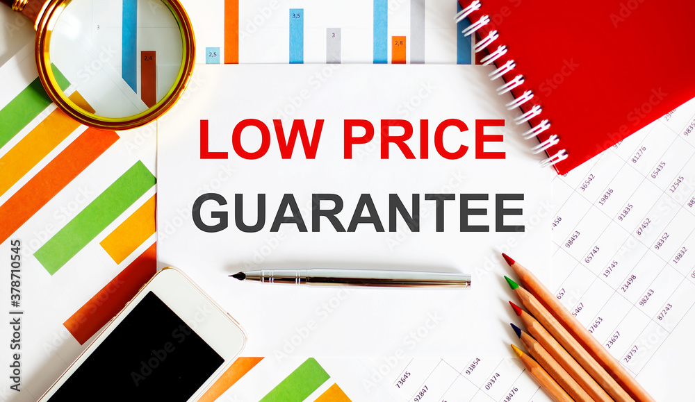 Text LOW PRICE GUARANTEE on the notepad with office tools, pen on financial report