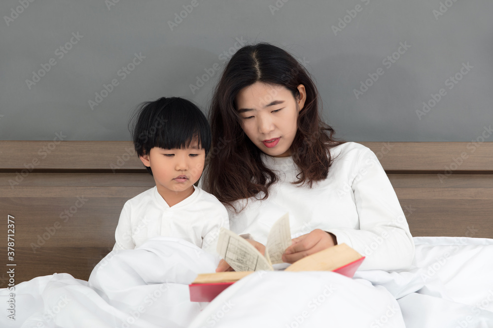 Young mother sitting on the bedside telling stories to children Young mother sitting on the bedside telling stories to children