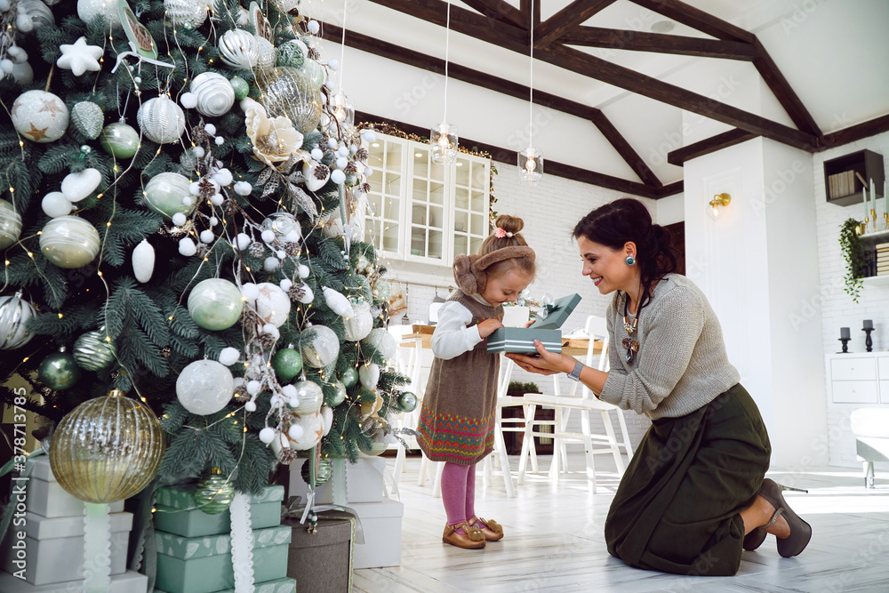 mother and daughter in dresses near the Christmas tree with gifts