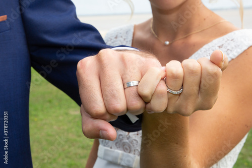 bride and groom present their fists with the wedding rings on their fingers after celebration