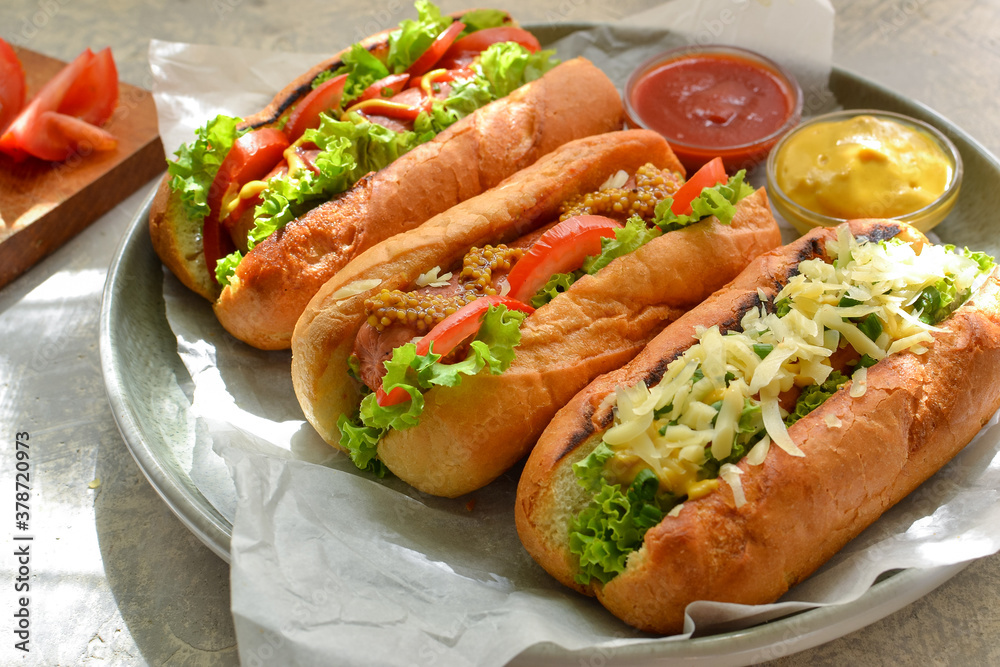 Hot dogs with various fillings. Dark background. food background with copy space. Hot dogs with mustard and ketchup, lettuce, cheese and tomatoes. Close up Hot dogs with various fillings. Dark background. food background with copy space. Hot dogs with mustard and ketchup, lettuce, cheese and tomatoes. Close up