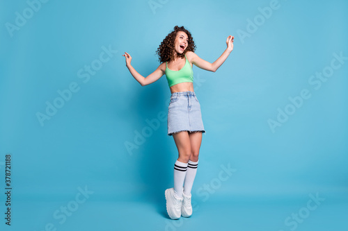 Fototapeta Naklejka Na Ścianę i Meble -  Full size photo of cute funky lady model look empty space arms air dancing class spotswear advert banner shocking prices wear green top jeans skirt isolated pastel blue color background