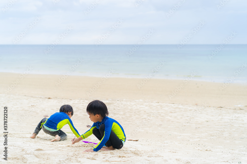 brothers are playing in the sand and swimming at the beach at an island in Thailand brothers are playing in the sand and swimming at the beach at an island in Thailand