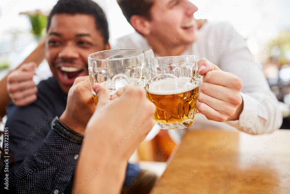 Männer trinken Bier und prosten sich zu im Biergarten