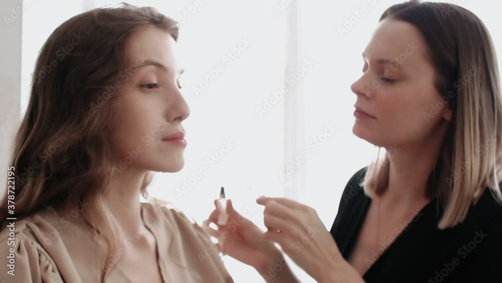 Makeup artist combs the model's eyebrows with a special eyebrow brush Makeup artist combs the model's eyebrows with a special eyebrow brush
