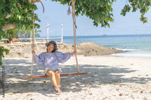 A woman is playing on the swing at the beach.