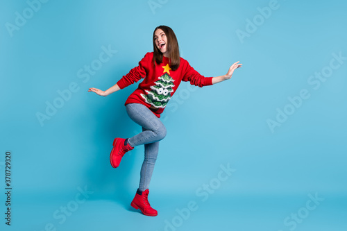 Full length body size photo of young brunette girl dancing smiling entertaining wearing red christmas sweater isolated on blue color background