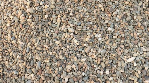 round river gravel of different shades is scattered on a horizontal surface as a textured natural background