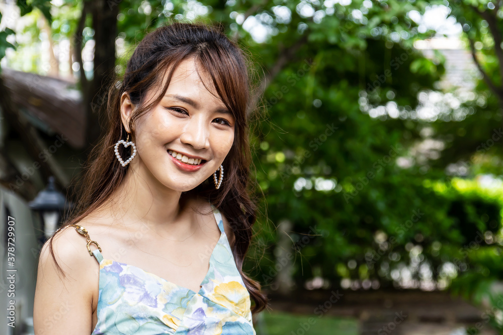 Outdoor portrait of beautiful young asian woman smiling brightly at the camera.