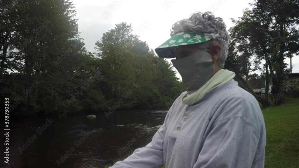 Woman attemps to catch a fish at the river while wearing a mask covid Woman attemps to catch a fish at the river while wearing a mask covid