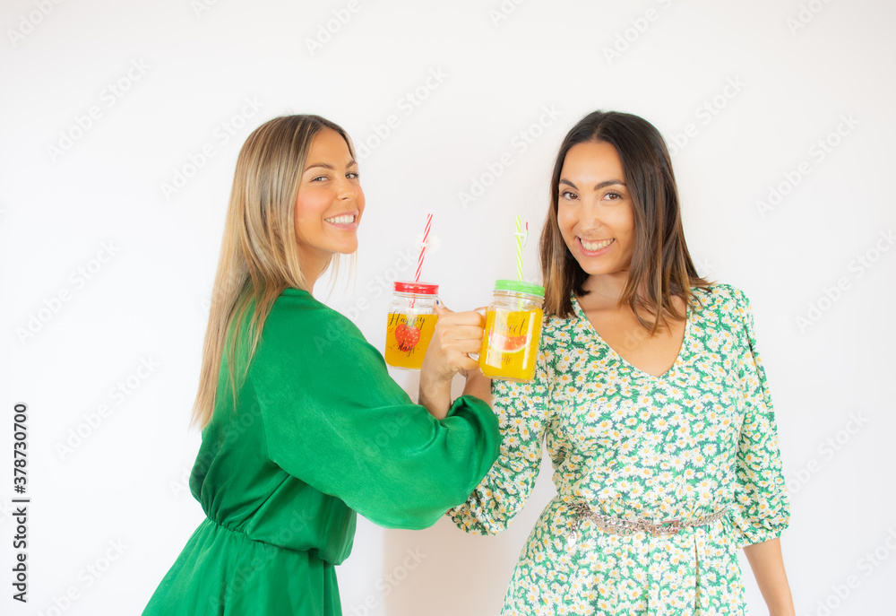 Women toasting with fruit juices while smiling Women toasting with fruit juices while smiling