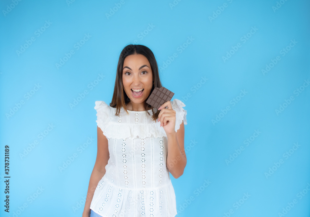 Woman holding a chocolate bar facing the camera with a funny expression Woman holding a chocolate bar facing the camera with a funny expression