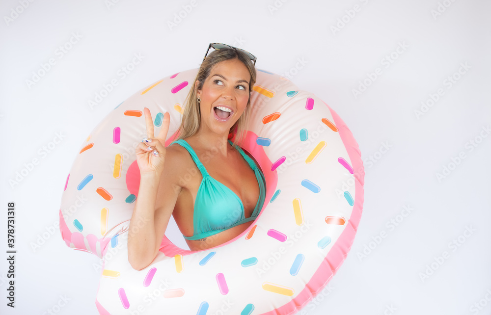 Fototapeta premium Blonde woman inside a giant toy doughnut making a victory symbol with a hand