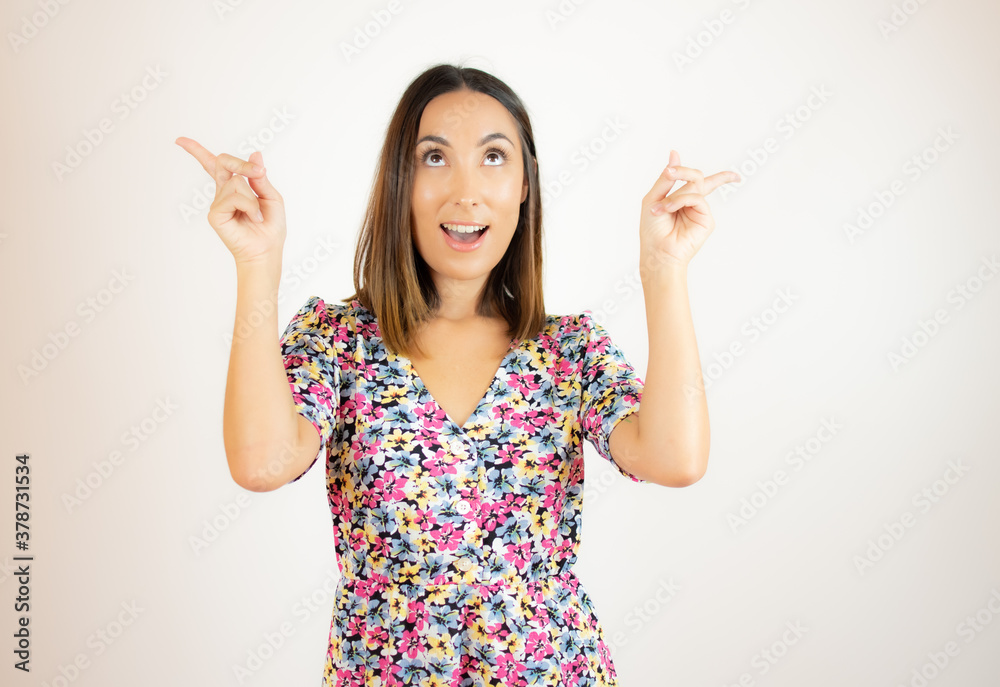 Woman in dress standing pointing out above with happy expression Woman in dress standing pointing out above with happy expression