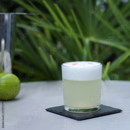 Pisco Sour cocktail in rock glass with slate coaster