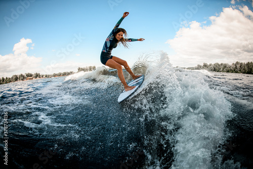 Active young woman in swimsuit vigorously ride the wave on surfboard