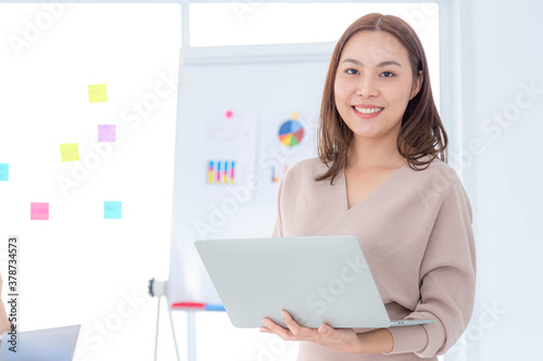 business woman holding laptop looking at camera at office indoors