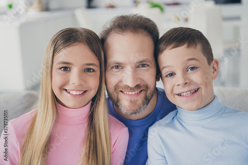 Idyllic family portrait of father with two kids boy girl toothy smile sit couch in house indoors