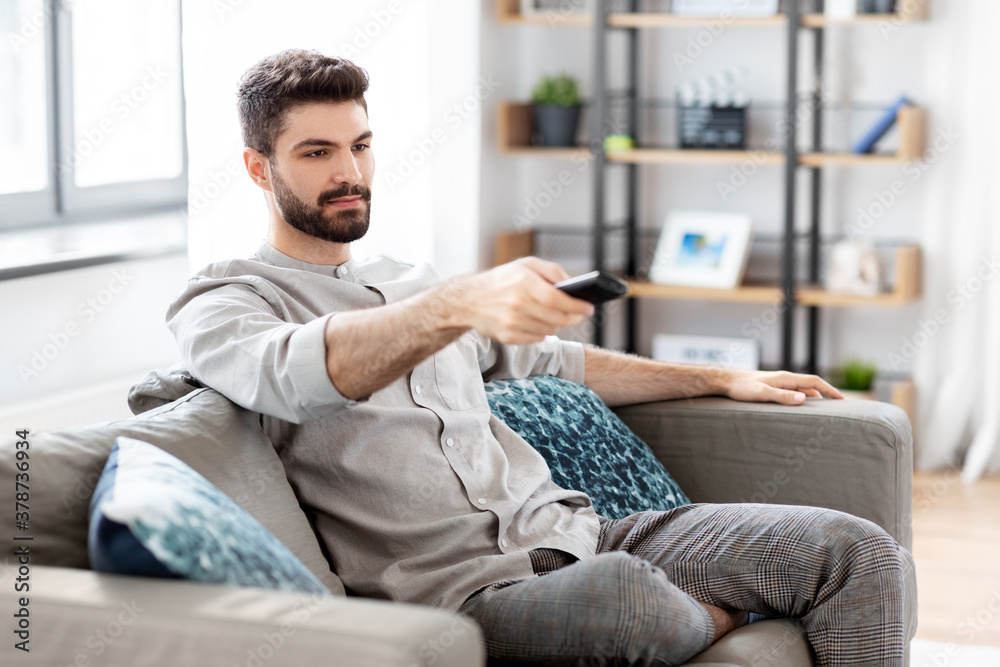 people and leisure concept - man with remote control watching tv at home