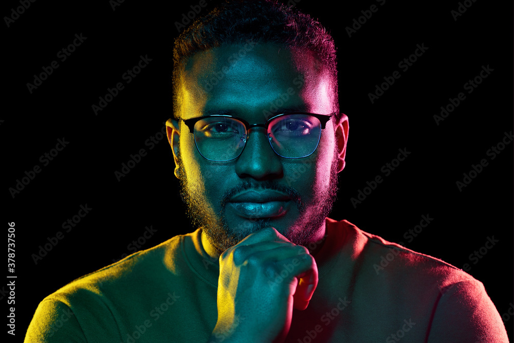 people and ethnicity concept - portrait of young african american man in glasses over black background